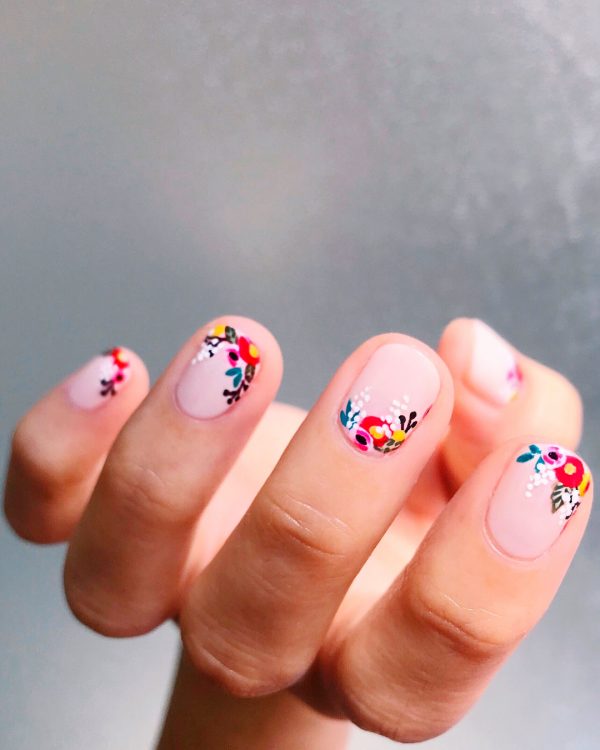 floral nails design short shaped uses nude pink gel polish as a base coat, and red, pink and yellow flowers on tips and bottoms