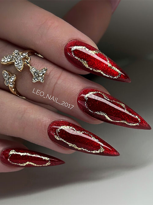 Long stiletto gel dark red nails adorned with abstract gold glitter nail art decorations