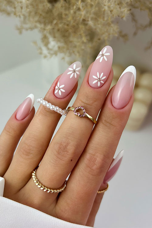 Classic long almond-shaped white French nails with two accent nude nails adorned with white daisy flowers
