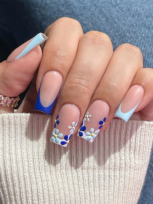 Cute classic light blue French nails with an accent dark blue nail and two white French nails adorned with flowers