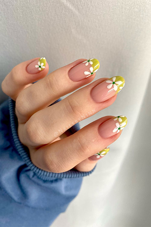 Long almond shaped pastel lime green French tip nails over nude base color with white daisy flower