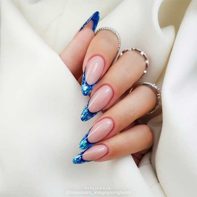 Cute blue French tip nails with glittery tips over almond shaped nails