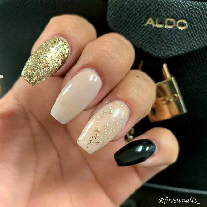 Cute coffin nails consists of nude acrylic coffin nails with gold glitter, accent gold glitter coffin nail, and accent black coffin nail