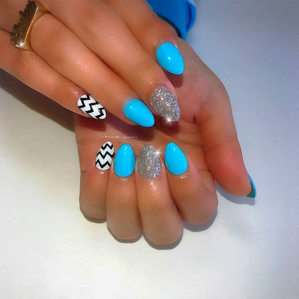 Gorgeous light blue acrylic nails with silver glitter nail and white nail with black zigzag!