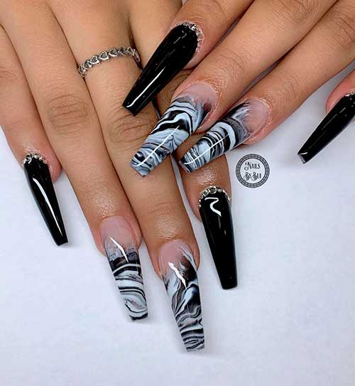 Long glossy black coffin nails with rhinestones and two accent white and black marble nails