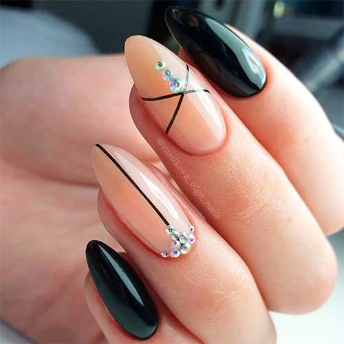 Cute black almond nails with two accent nails nude coloured with black strips and rhinestones!