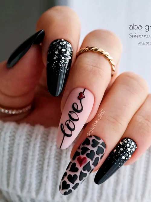 Long almond-shaped glitter black valentine’s nails 2023 with black and red hearts and love letters on nude accent nails