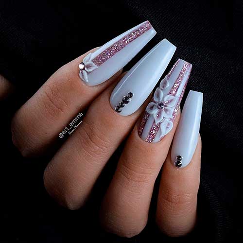 Beautiful light gray coffin nails with rhinestones, glitter, and an accent floral nail! Beautiful light gray coffin nails with rhinestones, glitter, and an accent floral nail!