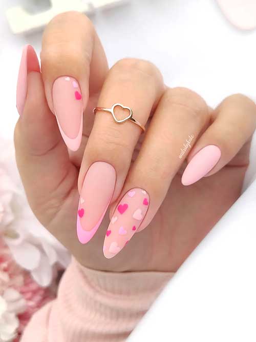 Long almond-shaped baby pink valentine’s day nails 2023 with heart shapes and two French accent nails