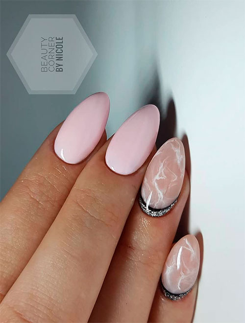light pink nails with two marble nails and silver glitter at the cuticles