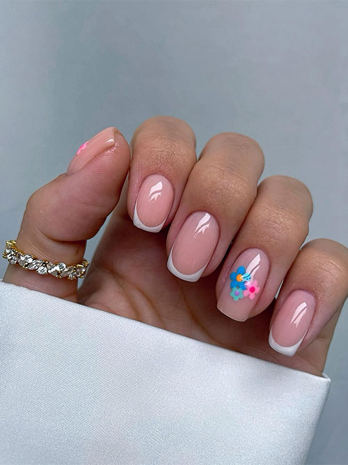 Classic white short French nails with pink, green, and blue flowers on two accent nails are the best nails ideas for spring