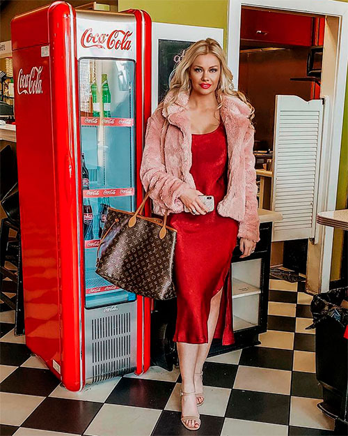 Woman wears a red slip dress under a pink fuzzy jacket which suits spring outfits 2019