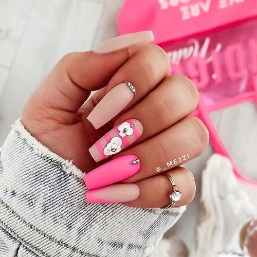 Gorgeous matte nude nails coffin shaped with rhinestones, pink striped nail with 3d flowers, matte pink nail, and pink tip french nail design Gorgeous matte nude nails coffin shaped with rhinestones, pink striped nail with 3d flowers, matte pink nail, and pink tip french nail design