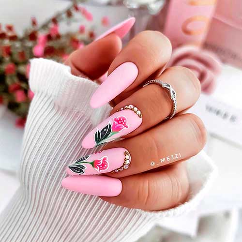 Cute baby pink almond nails with two accent nails with floral nail art and rhinestones!