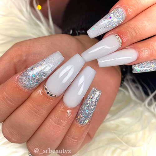 Elegant white acrylic nails with rhinestones and glitter accent nails Elegant white acrylic nails with rhinestones and glitter accent nails