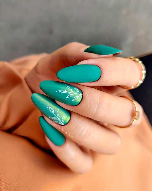 Cute matte emerald green nails almond shaped with two accent white fall leaves nails adorned with pollen Unicorn effect