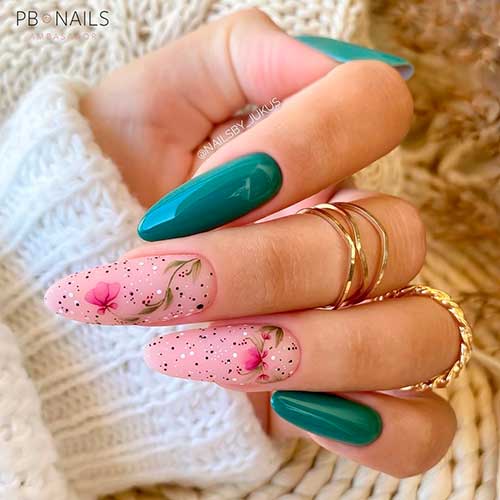 Gorgeous emerald green nails almond shaped with two accent floral nail art over nude pink base color with black & white dots