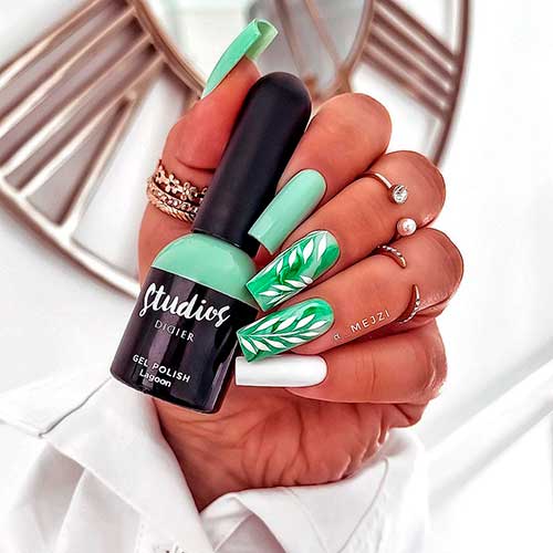 Cute long square shaped mint green nails with two accent fall leaves’ nails and accent white nail