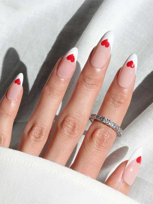 Chic almond French tip nails featuring a nude base, white tips, and playful red hearts, ideal for adding romance to your look.