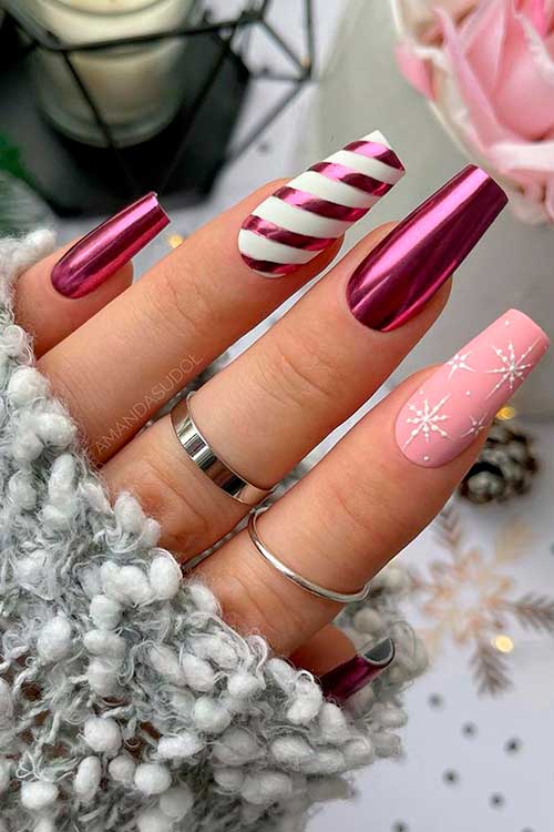 Chrome Pink Christmas Nails Chic coffin-shaped Christmas nails consists of chrome pink nails, Accent candy nails, and a matte light pink accent nail with white snowflakes.
