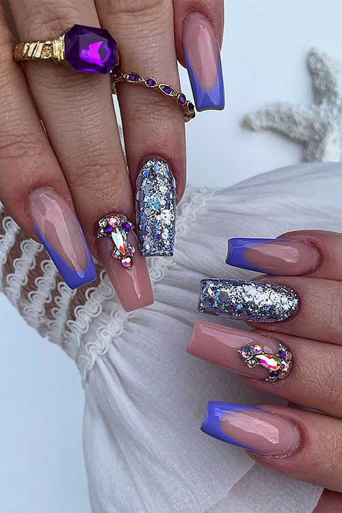 Long coffin-shaped purple French tip nails with a nude accent nail adorned with rhinestones and a silver glitter accent nail Long coffin-shaped purple French tip nails with a nude accent nail adorned with rhinestones and a silver glitter accent nail
