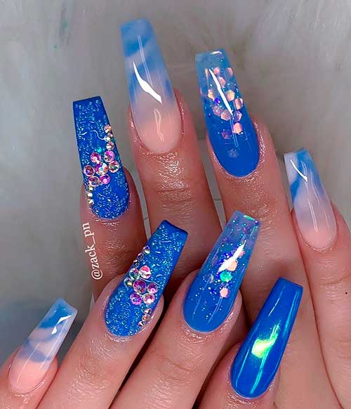 Glossy royal blue coffin nails with heart glitter, sugar glitter, rhinestones, and marble effects