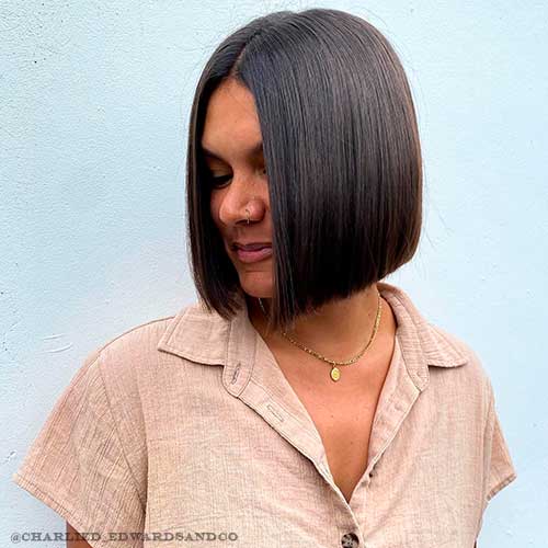 Black hair with short sleek bob haircut with middle part that gives younger appearance