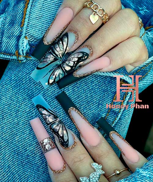 Long coffin matte black French tip nails with butterflies on clear accents and adorned with gold glitter