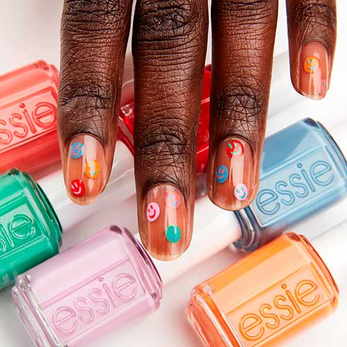Short nude nails with colored smile faces nail art design that uses the Limited Edition Essie Movin’ & Groovin’ Collection