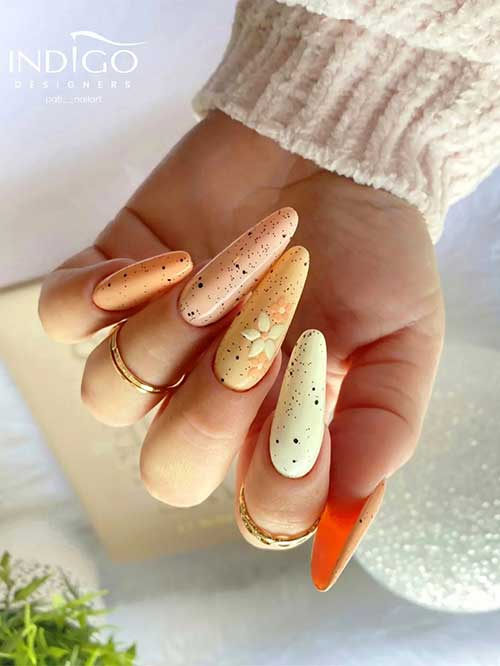 Long almond different shades of yellow easter nails with black speckles and flowers on an accent nail