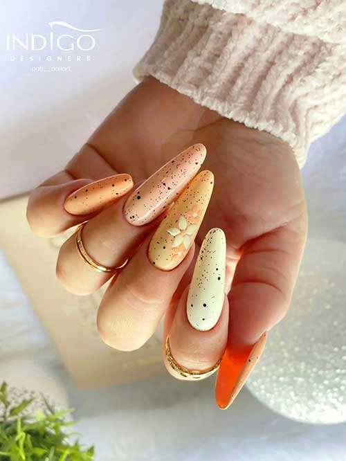 Long almond different shades of yellow easter nails with black speckles and flowers on an accent nail Long almond different shades of yellow easter nails with black speckles and flowers on an accent nail