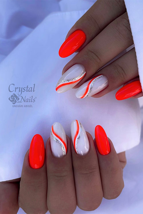 Long almond-shaped neon orange nails with two accent milky white nails adorned with white, silver glitter, and orange swirls Long almond-shaped neon orange nails with two accent milky white nails adorned with white, silver glitter, and orange swirls