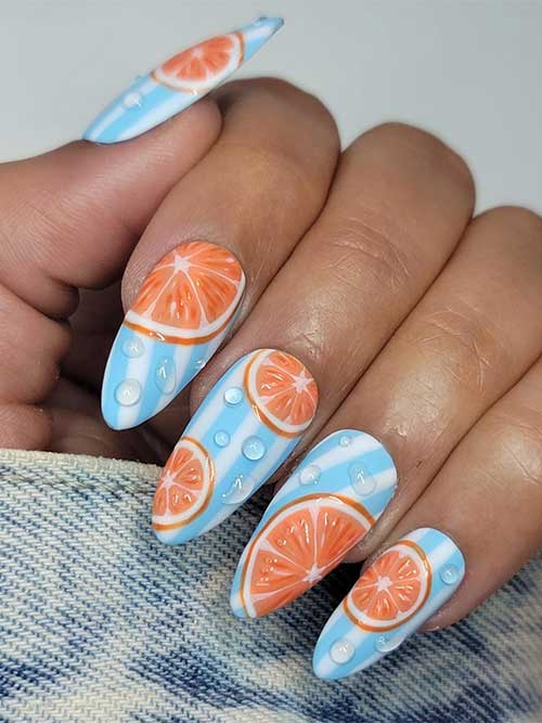 Juicy citrus nails with water droplet nail art over light blue and white striped nail art design