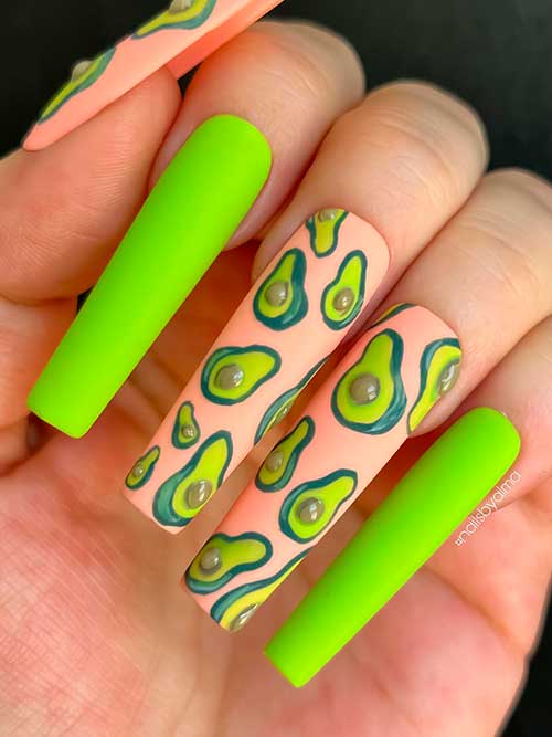 Long matte neon green and peach nails adorned with avocado fruits for summer 2022