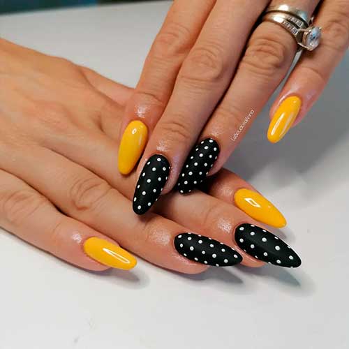 Long almond shaped yellow and black nails with white polka dots for summer 2022