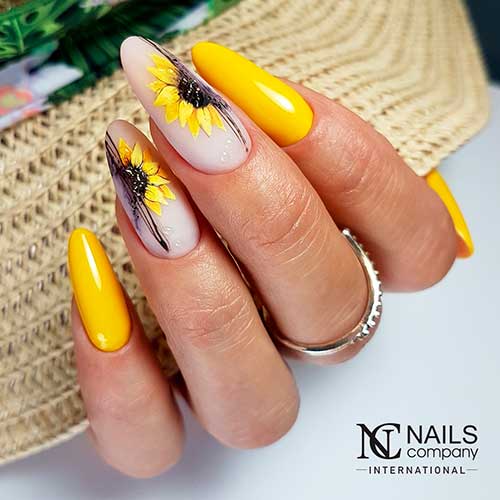 Yellow nails with sunflowers on accents Long almond shaped glossy yellow nails with sunflowers on two nude base color accents