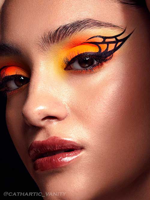 Black graphic liner with neon orange and yellow eyeshadows for Fall 2022