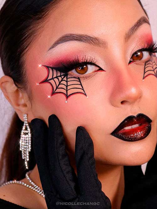 Black and red spider web eye makeup with rhinestones and vampy red lips