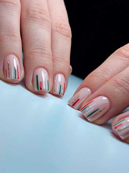 Festive Short Christmas Nails Festive Short Nude Simple Christmas Nails with red, green, gold glitter, and white vertical lines in random patterns