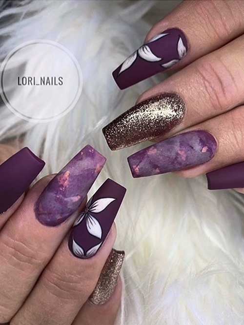 Matte coffin spring purple nails 2023 with white flowers, gold glitter, and marble accent nails