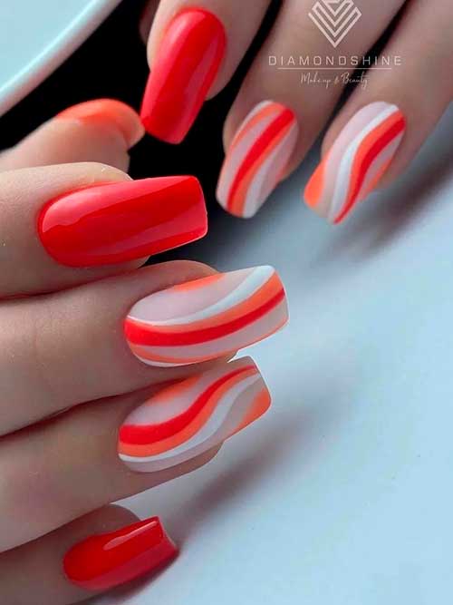 Red nails with orange, white, and red swirls on nude accent nails Red nails with orange, white, and red swirls on nude accent nails