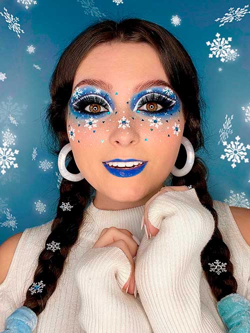 Winter makeup look using white snowflakes, blue eyeshadow, and blue lips for Christmas 2022