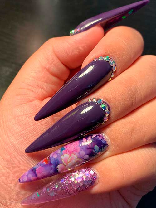 long stiletto dark purple nails with flowers, rhinestones, and glitter accent nails