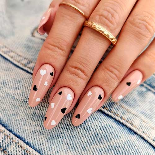Cute almond shaped nude nails 2023 with black and white tiny hearts that suits valentine’s day