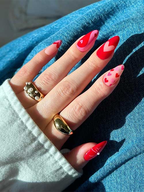Glossy red nails almond shaped and adorned with heart nail art designs and a nude accent adorned with pink and red hearts