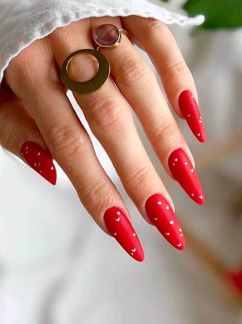 Long almond matte red valentine nails with tiny white hearts to celebrate Valentine’s Day