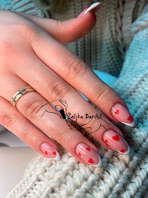 Long almond shaped white French nails with red hearts to celebrate Valentine’s Day 2023