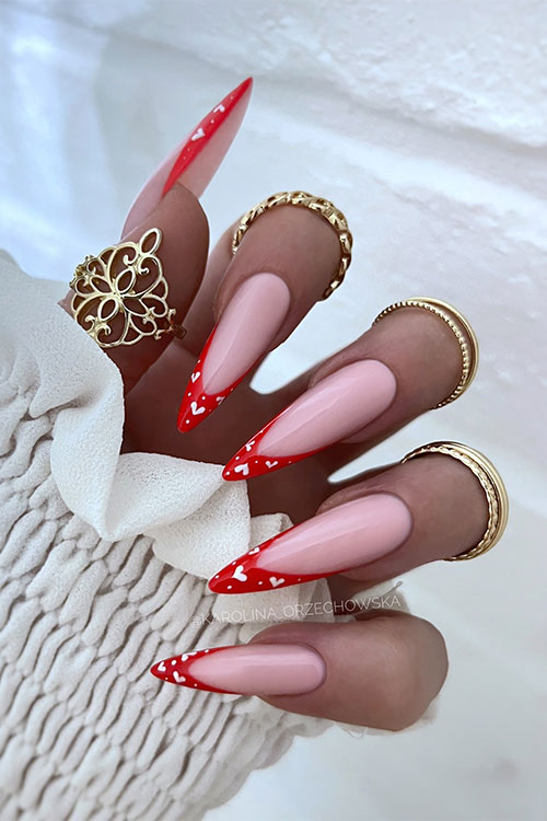 Long glossy stiletto red French manicure with white hearts and dots on the nail tips Long glossy stiletto red French manicure with white hearts and dots on the nail tips