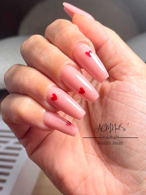 Long nude coffin valentine nails with small red hearts to celebrate love in 2023
