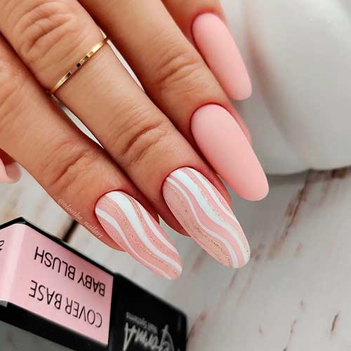 Long round shaped matte pink nude nails with delicate white and gold glitter swirls on two accent nails